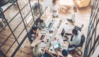 Top view of multiracial young creative people in modern office. Group of young business people are working together with laptop, tablet, smart phone, notebook. Successful hipster team in coworking. Freelancers.